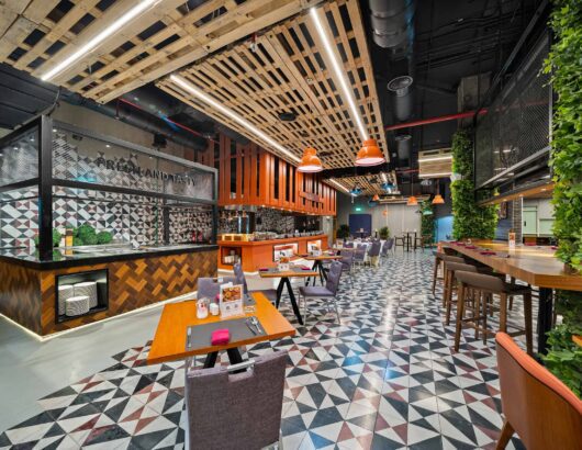 Modern restaurant interior with wooden accents, green walls, and a variety of seating options.