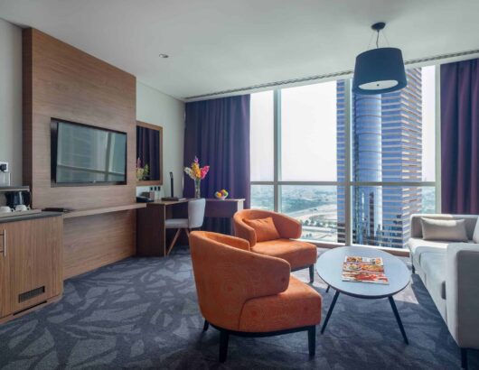 Spacious hotel room with city views, a comfortable seating area, and a work desk.