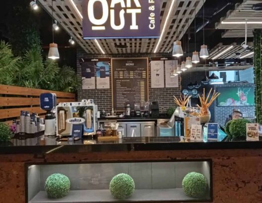 Cafe interior with a wooden counter, coffee machines, and a menu board.