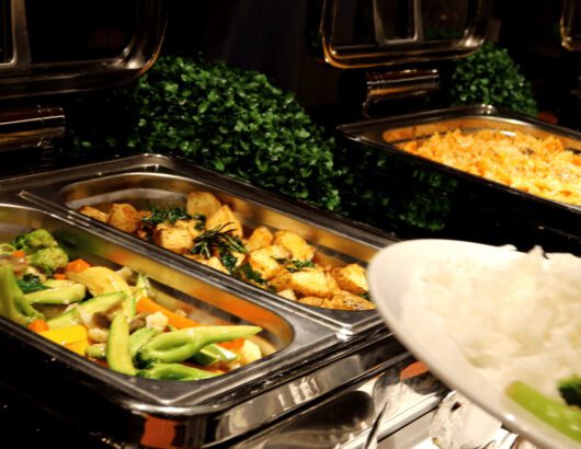 A buffet spread with roasted potatoes, vegetables, and pasta.