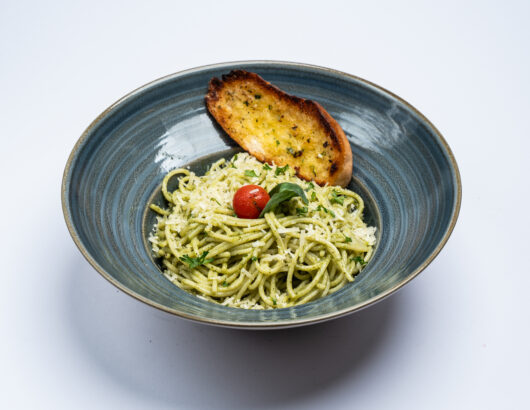 Creamy pesto pasta with a side of garlic bread, a classic Italian dish.