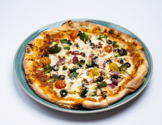 A vegetable pizza with broccoli, tomatoes, olives, and onions, topped with melted cheese.